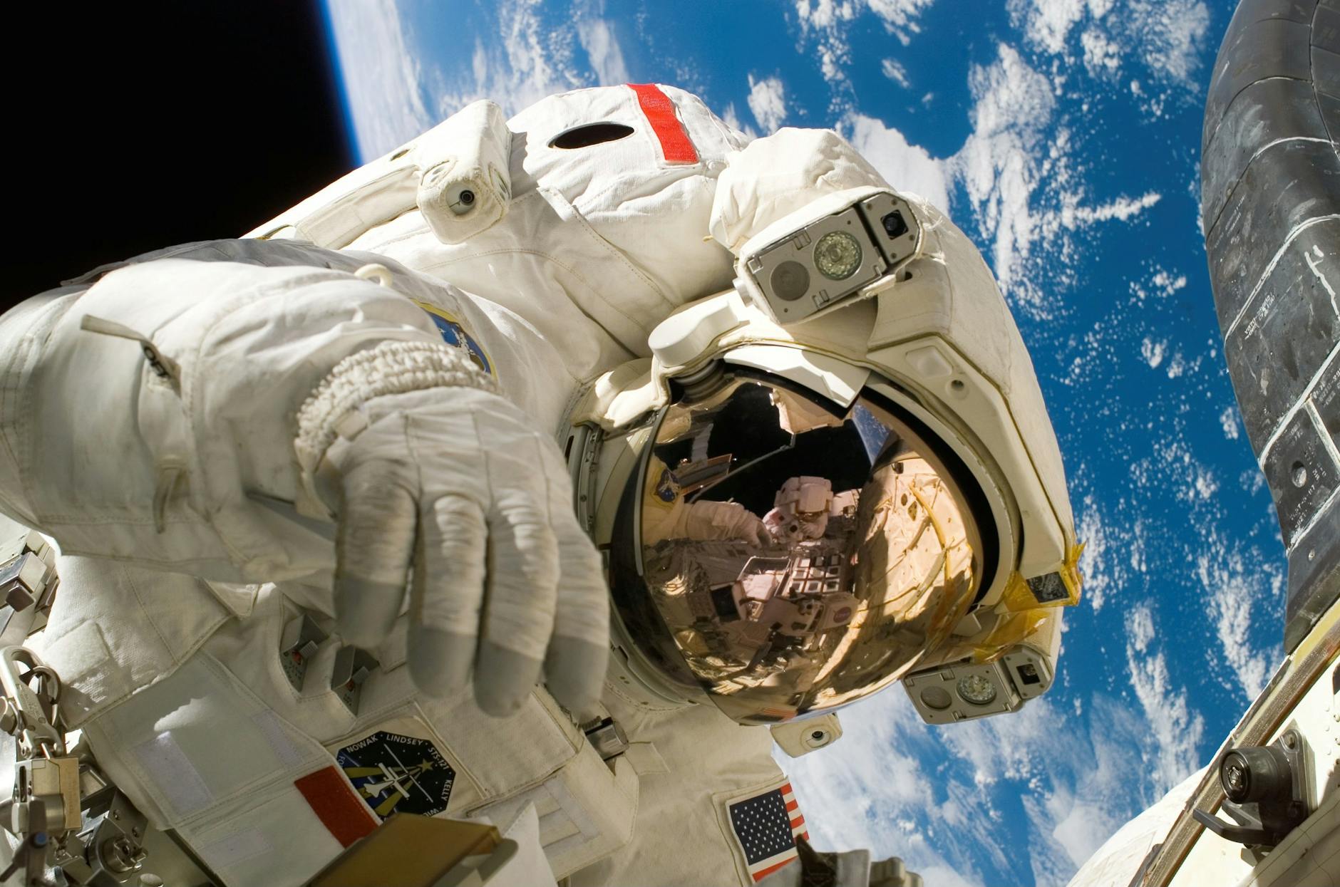 Astronaut floating in space during a spacewalk, visible Earth in the background.